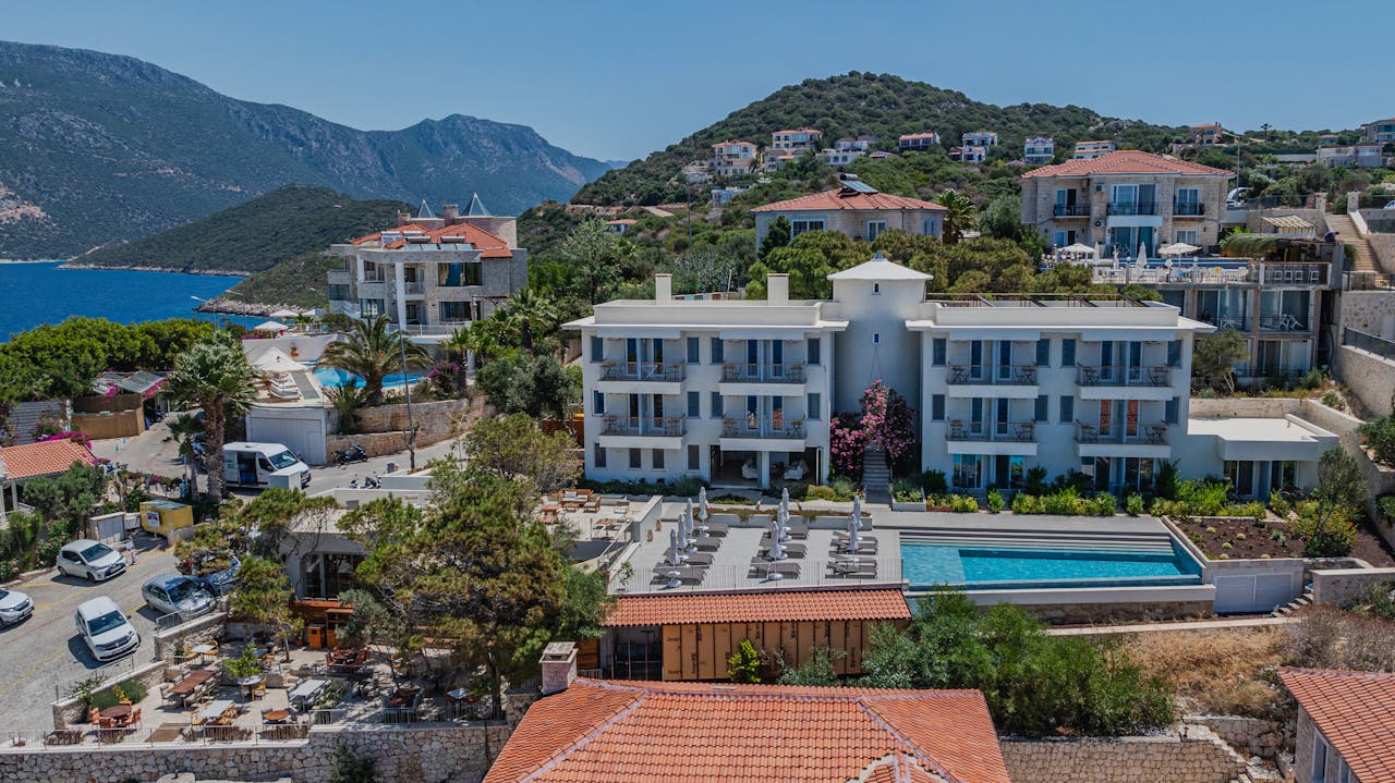 A serene aerial view of a coastal Mediterranean resort with lush surroundings.